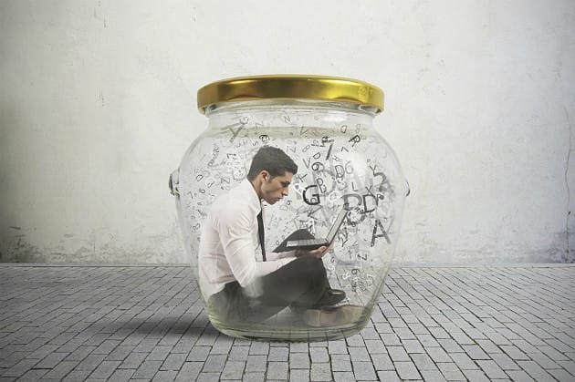 A professional worker sitting trapped inside a closed glass jar surrounded by letters